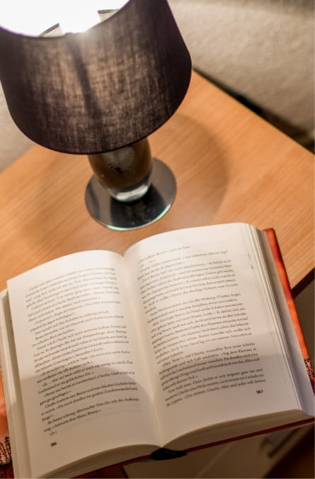 Buch mit Lampe am Bett